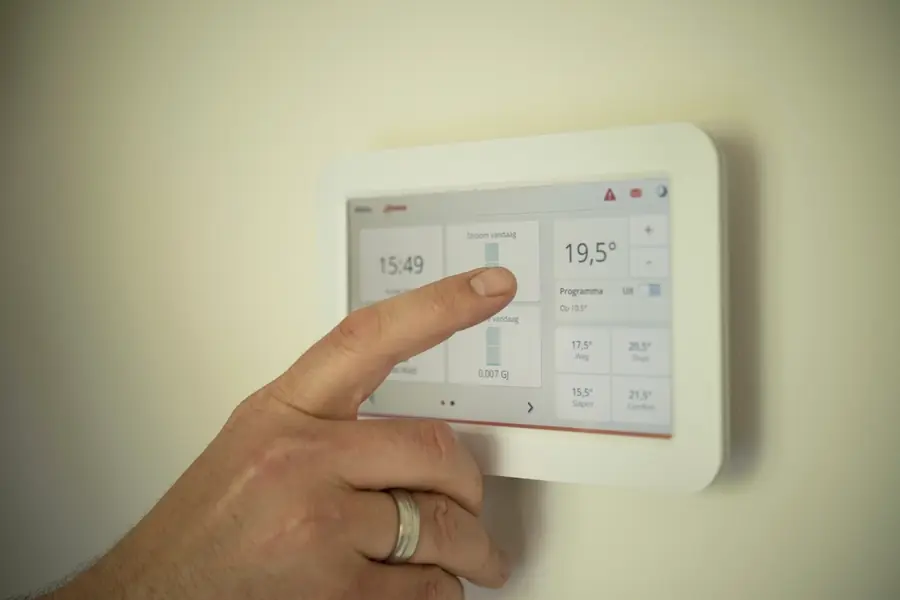 Mano ajustando un termostato en la pared